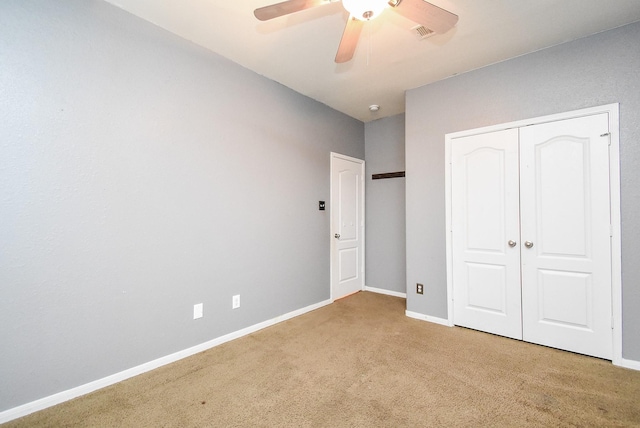 unfurnished bedroom featuring ceiling fan, a closet, and light carpet