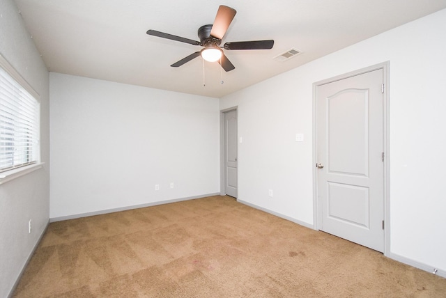 carpeted spare room with a ceiling fan, baseboards, and visible vents