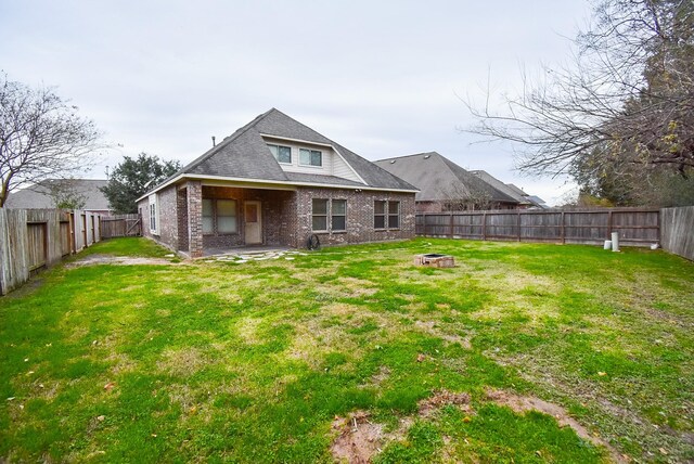 rear view of house with an outdoor fire pit and a yard