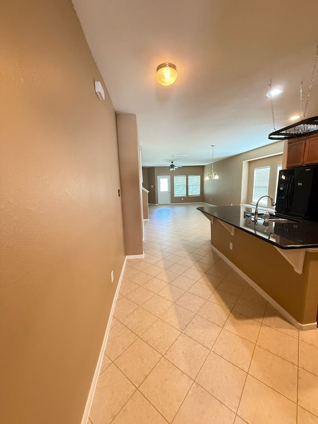 kitchen with a sink, dark countertops, a breakfast bar area, and freestanding refrigerator