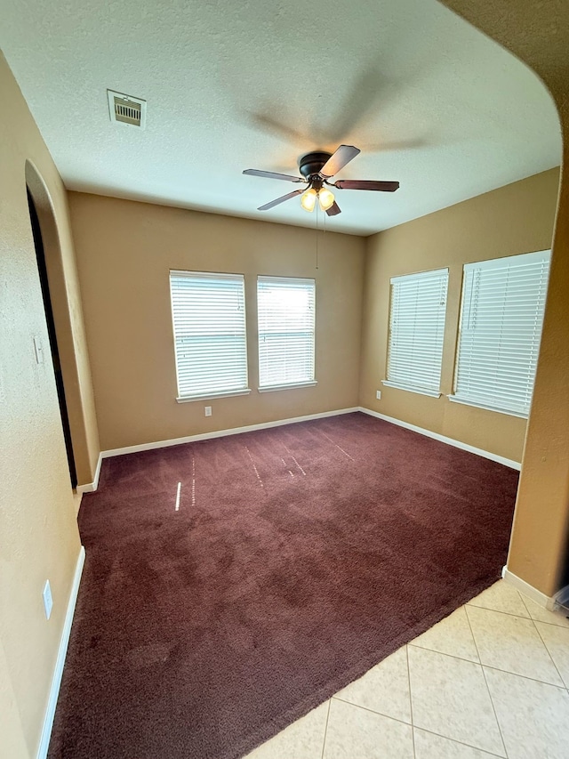 carpeted empty room with visible vents, ceiling fan, a textured ceiling, and baseboards