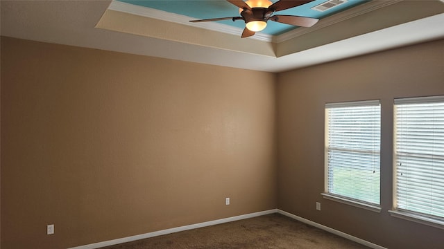 spare room featuring visible vents, plenty of natural light, a raised ceiling, and dark colored carpet