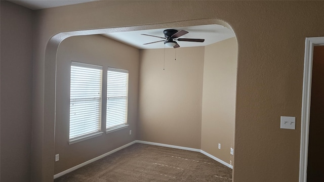 carpeted spare room with a ceiling fan and baseboards