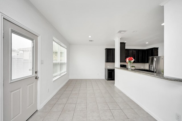 kitchen featuring light stone counters, stainless steel refrigerator with ice dispenser, and light tile patterned flooring