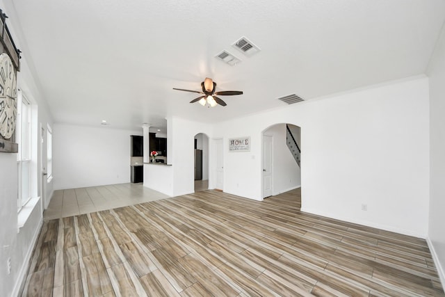 unfurnished living room with ceiling fan and crown molding