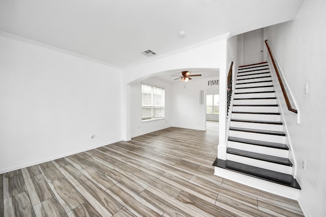 unfurnished living room with ceiling fan and crown molding