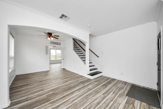 unfurnished living room with ceiling fan and ornamental molding