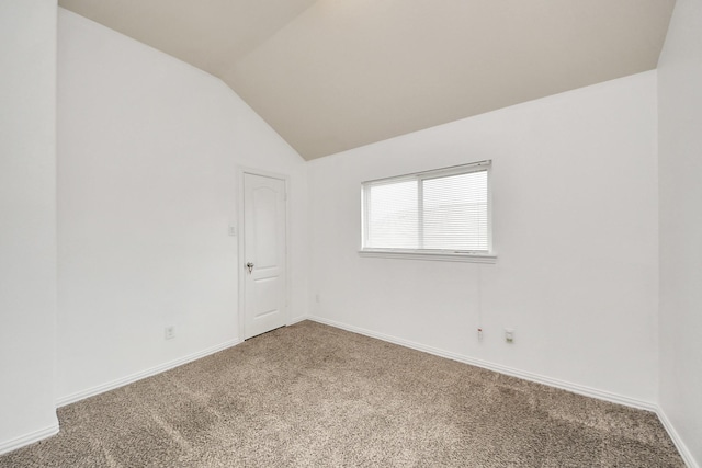 carpeted empty room with vaulted ceiling