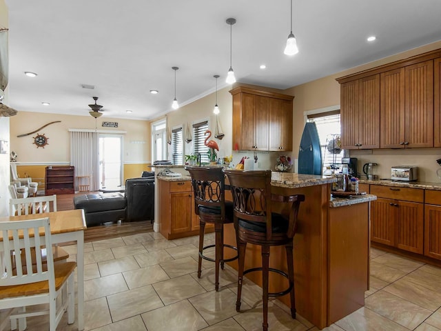 kitchen featuring ceiling fan, pendant lighting, stone counters, and a kitchen island