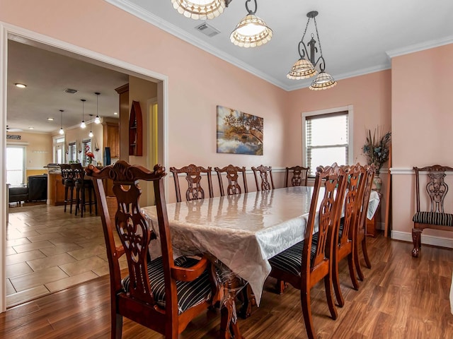 dining room featuring ornamental molding, wood-type flooring, and plenty of natural light