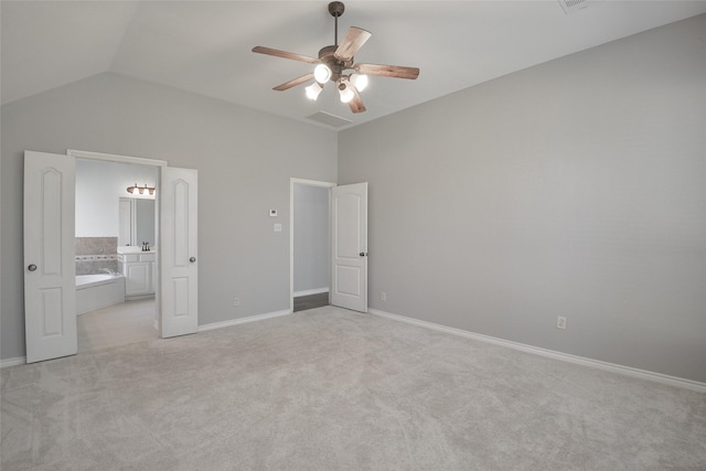 unfurnished bedroom featuring ensuite bath, ceiling fan, light carpet, and lofted ceiling