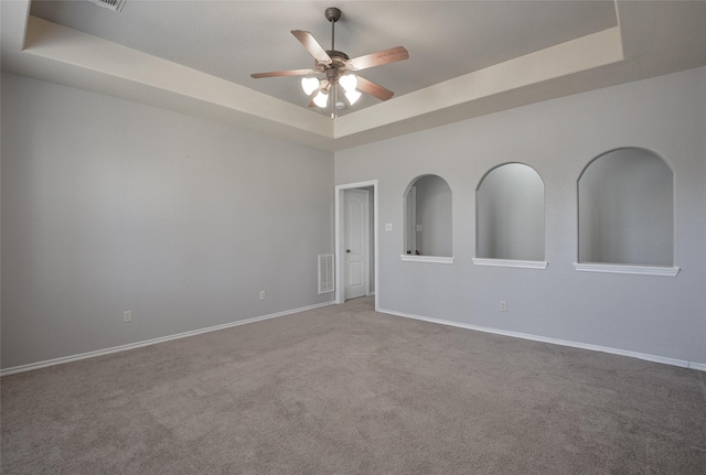 spare room featuring ceiling fan, light colored carpet, and a raised ceiling