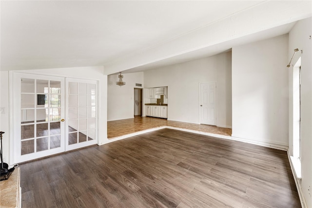 unfurnished room featuring lofted ceiling, french doors, and hardwood / wood-style flooring