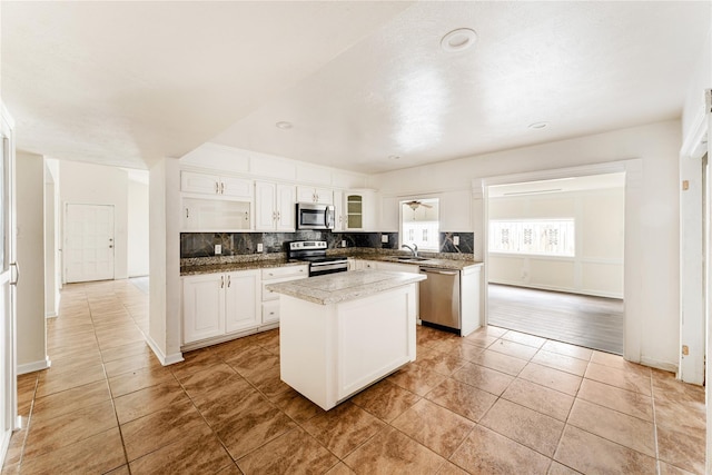 kitchen featuring light tile patterned floors, white cabinetry, stainless steel appliances, a kitchen island, and sink