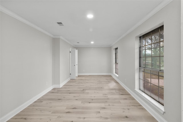 corridor featuring light wood-type flooring, ornamental molding, and a healthy amount of sunlight