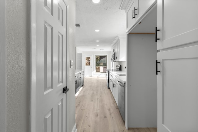 hallway with light hardwood / wood-style floors and a textured ceiling