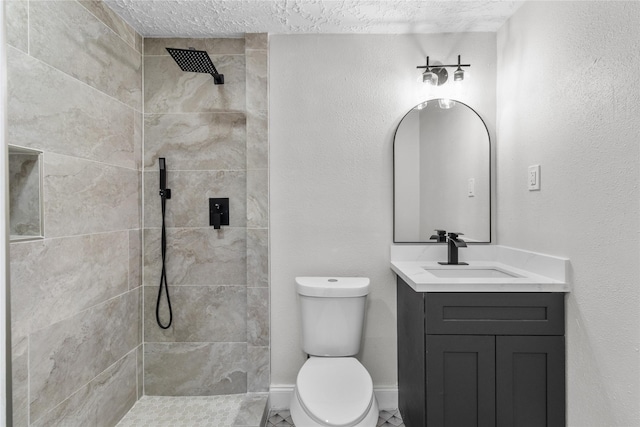 bathroom featuring toilet, vanity, and a tile shower