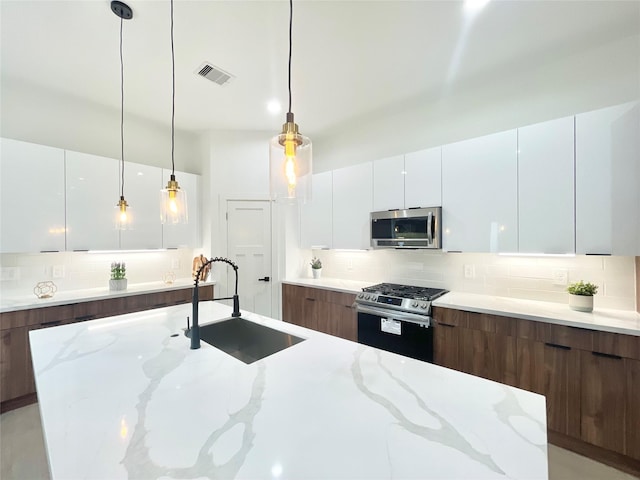 kitchen featuring pendant lighting, white cabinets, stainless steel appliances, sink, and light stone counters