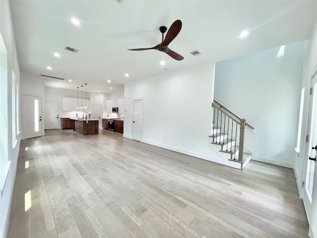 unfurnished living room featuring ceiling fan and light wood-type flooring