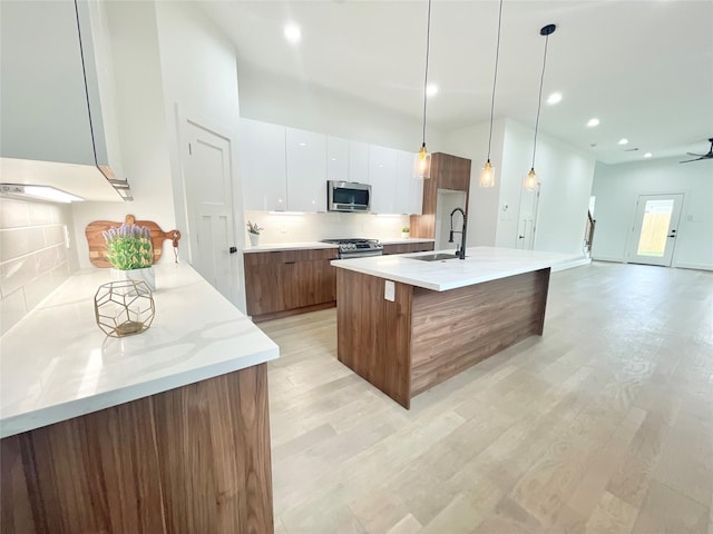 kitchen featuring sink, white cabinetry, hanging light fixtures, a center island with sink, and stainless steel appliances