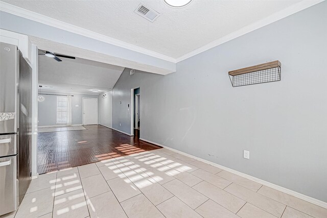 spare room with light tile patterned flooring, ornamental molding, and a textured ceiling