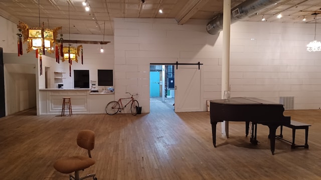 interior space featuring a barn door, concrete block wall, wood finished floors, and track lighting