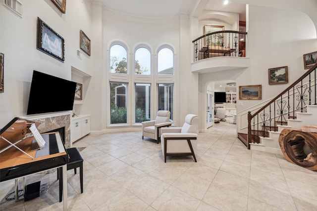 living room featuring ornamental molding, a premium fireplace, and a high ceiling