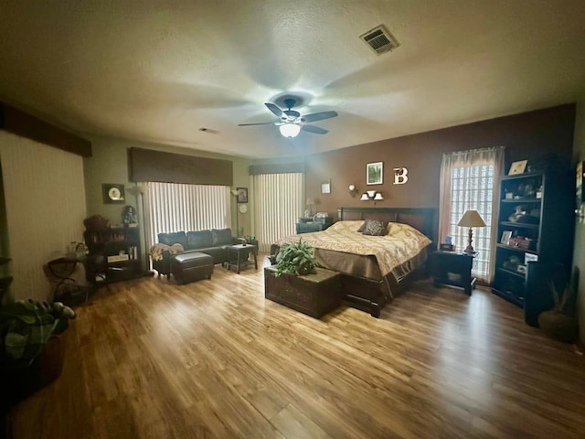 bedroom with a textured ceiling, ceiling fan, and wood-type flooring