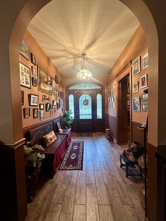 foyer with wood-type flooring, a notable chandelier, and a textured ceiling