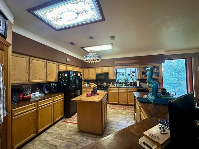 kitchen with pendant lighting, black appliances, butcher block countertops, a kitchen island, and ornamental molding