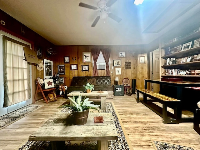 living room with ceiling fan, cooling unit, wood walls, and light hardwood / wood-style floors