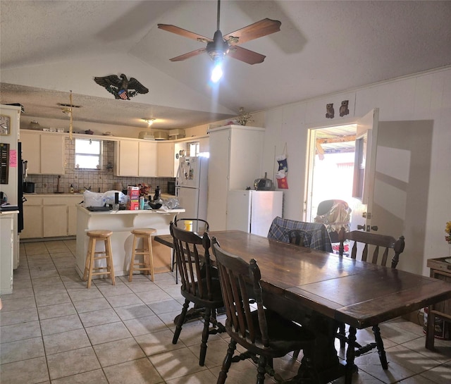 tiled dining room with a textured ceiling, ceiling fan, and lofted ceiling