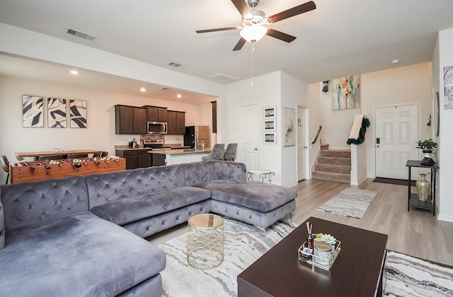 living room featuring light wood-type flooring, ceiling fan, and sink