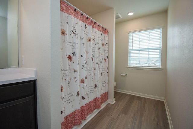 full bathroom with toilet, shower / bathtub combination with curtain, hardwood / wood-style flooring, and vanity