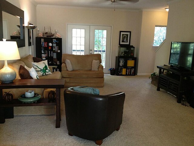 carpeted living room with ceiling fan, ornamental molding, and french doors