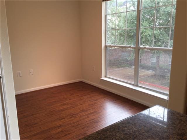 unfurnished room with plenty of natural light, baseboards, and dark wood-style flooring