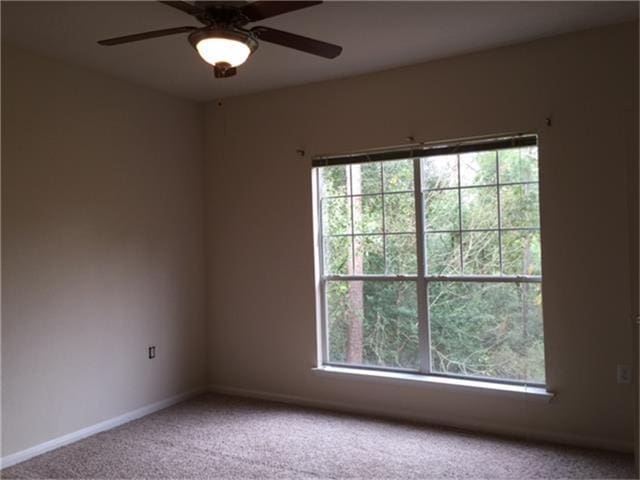 carpeted empty room featuring a ceiling fan and baseboards