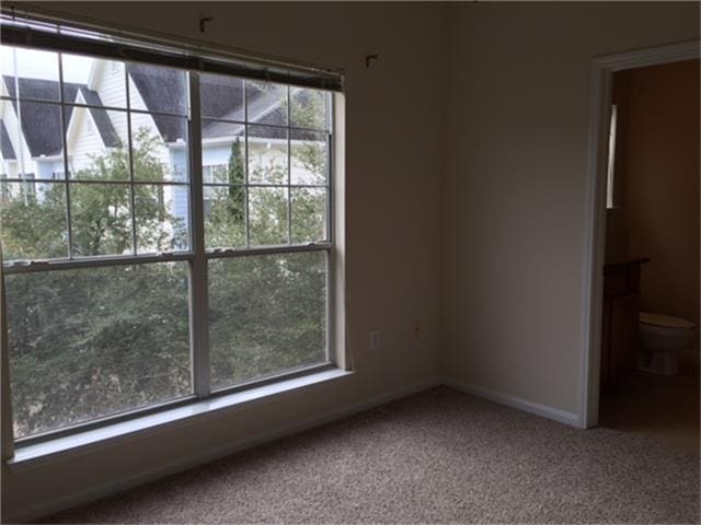 carpeted empty room featuring baseboards