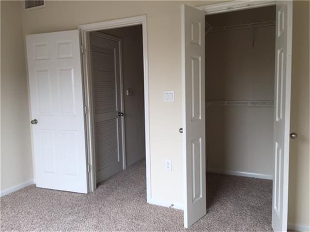 unfurnished bedroom featuring carpet, a closet, visible vents, and baseboards