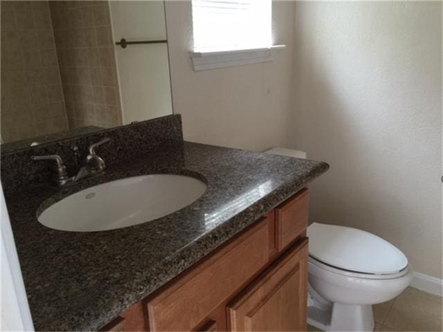 bathroom featuring toilet, baseboards, vanity, and tile patterned floors