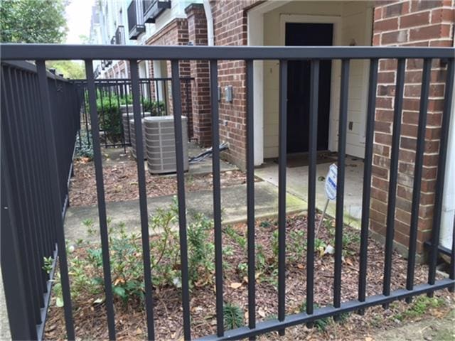 view of gate with fence and central air condition unit