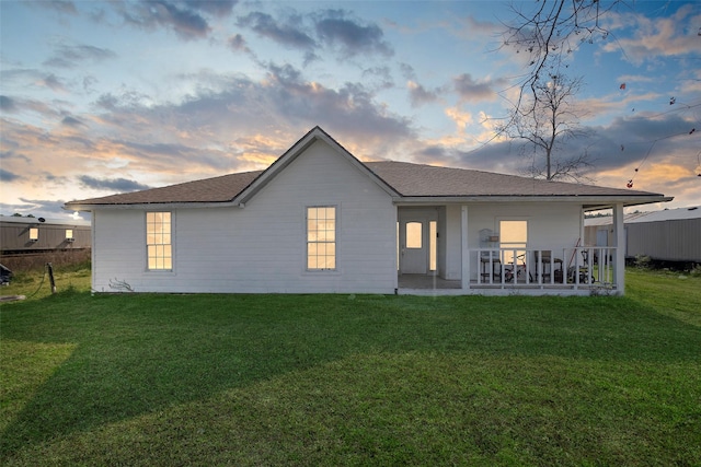 back house at dusk featuring a yard