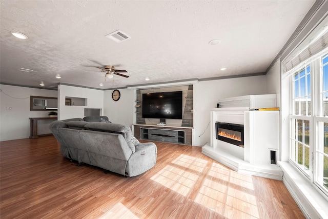 living room with hardwood / wood-style flooring, a textured ceiling, crown molding, and ceiling fan