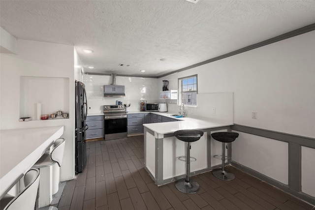 kitchen featuring gray cabinets, a breakfast bar, kitchen peninsula, sink, and stainless steel appliances