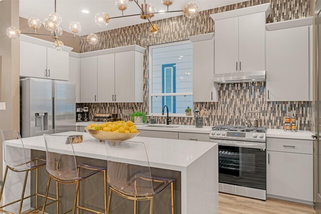 kitchen with appliances with stainless steel finishes, white cabinetry, hanging light fixtures, and sink