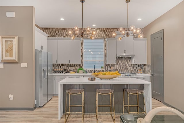 kitchen with pendant lighting, stainless steel fridge, and a kitchen island