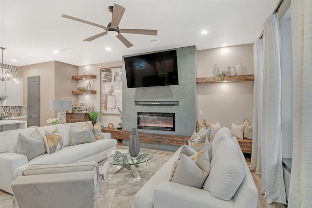 living room featuring ceiling fan, light wood-type flooring, and a fireplace