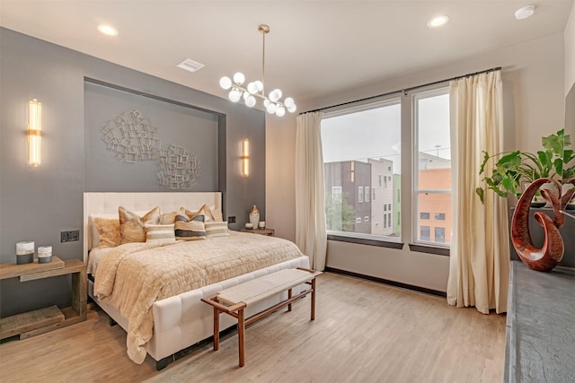 bedroom with multiple windows, light hardwood / wood-style floors, and a notable chandelier