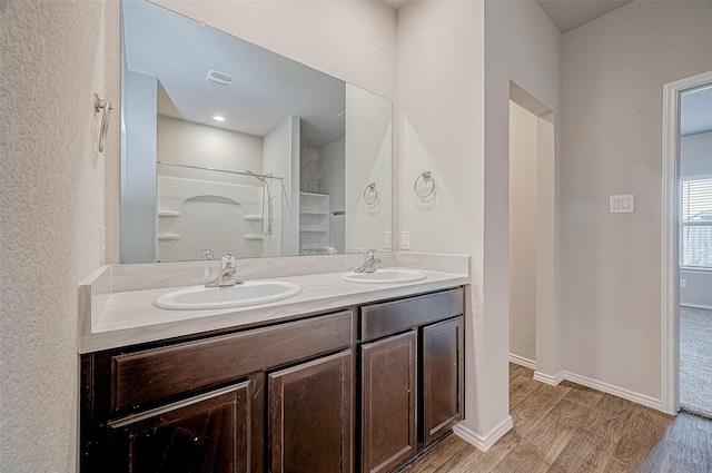 bathroom with wood-type flooring, walk in shower, and vanity