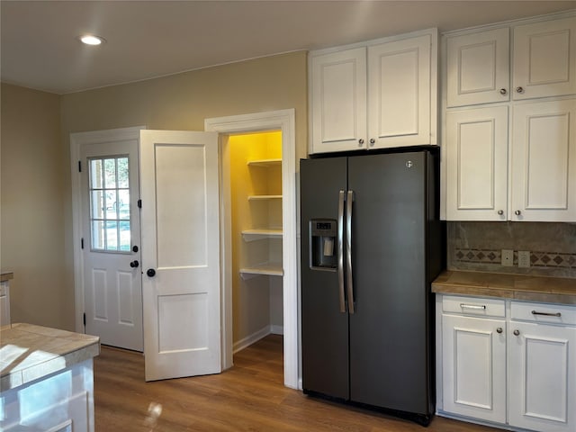 kitchen featuring stainless steel refrigerator with ice dispenser, white cabinets, and tasteful backsplash